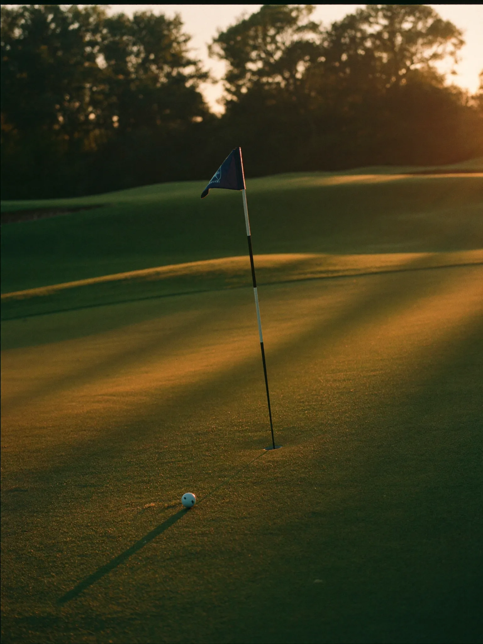 Fahne am Grün eines Golfplatzes im goldenen Morgenlicht